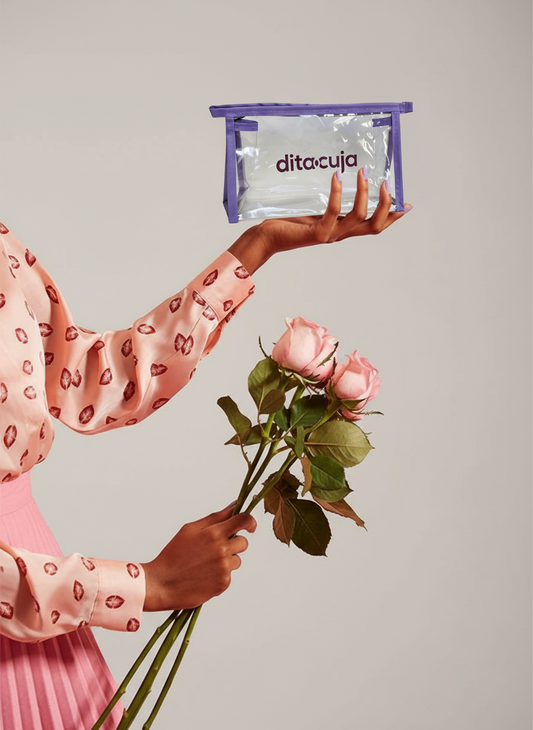Imagem de mãos femininas segurando necessárie da Ditacuja e rosas